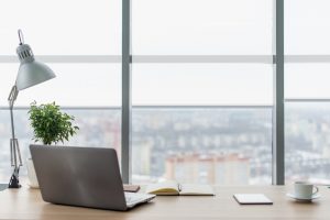 Workplace with notebook laptop Comfortable work table in office with windows and city view